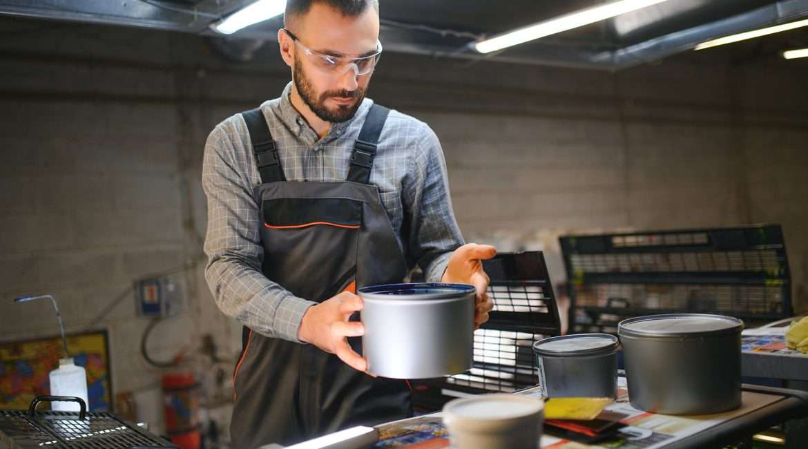 printing house, experimented technician works on UV printer. Production work.